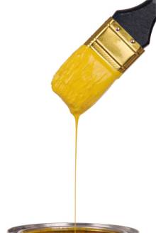 Yellow paint splashing out of brush. Isolated on white background